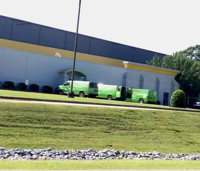 Green SERVPRO vehicles parked outside a commercial facility.