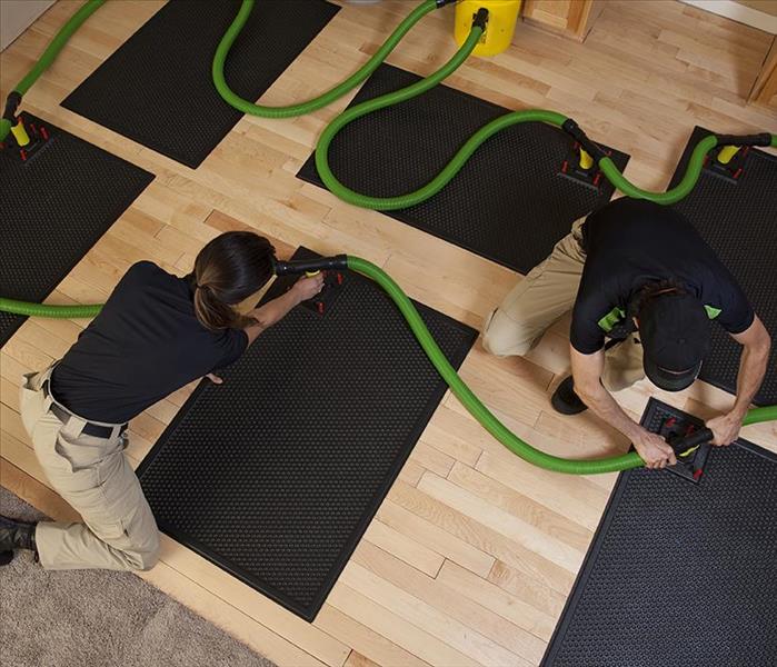 SERVPRO technicians placing a mat drying system on a floor.